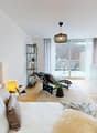 modern bedroom with a large bed, balcony, wooden floor, white walls, decorative items, and a view of the outside