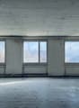 empty room with large windows, white walls, concrete floor, three windows, baseboard heating