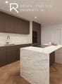 Central kitchen island, white marble countertops, dark wood cabinets, built-in appliances, hardwood flooring