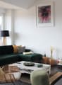 Living room with green sofa, coffee table, wooden chair, lamp, fireplace, and large windows