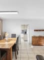 large windows, wooden dining table, chairs, wooden cupboard, bright kitchen