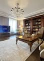 A large room with wooden flooring and furniture, chandelier, bookcase, couch, TV, table, chairs, and rugs.
