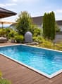Wooden deck, swimming pool, outdoor sofa, umbrella, plants, trees