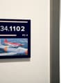 The image shows a framed display with the number 34.1102 and the label 'PC-3'. The display also includes a photograph of a red and white aircraft, likely a military jet or trainer aircraft.