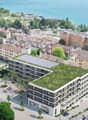 Multi-story building, solar panels on the roof, greenery, water body nearby, parking area, city skyline in the background