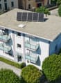 3 story house, white exterior, solar panels on roof, balconies on each floor