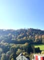 Mountains, trees, houses, smoke from chimney, clear blue sky, a valley in the background