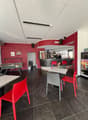 red wall, black tiled floor, counter with chairs, foosball table, two tables with chairs