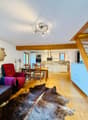 open plan living room and kitchen, wooden floor, dining table, chairs, sofa, radiator, wooden beams, kitchen with microwave, oven, sink, cabinets