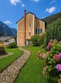 2 story house, brown brick, green shutters, garden, gravel path, mountain view