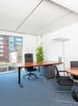 modern office room, white walls, blue carpet, wooden desks and chairs, large glass windows