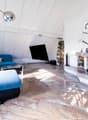 living room with fireplace, blue sofa, coffee table, TV, floor lamp, wooden floor