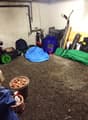 The image shows a cluttered garage space with various items such as tools, equipment, and storage containers scattered around the floor.