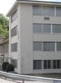 5 story building, white exterior, multiple windows, parking lot, trees in the background