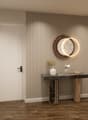 Entrance hall with wooden floor, white door, decorative table, round mirror, and decorative items