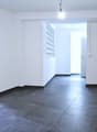 Empty room, white walls, black tiled floor, two doors, one with glass panel