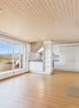 wooden floor, white walls, large windows, balcony, fireplace, kitchen with white cabinets