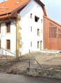 Modern 2 story house, wood exterior, red roof, large windows, balcony