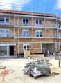 under construction, brick wall, glass windows, metal scaffolding, open doors, construction materials