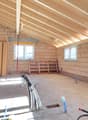 unfinished room, wooden beams, brick walls, three windows, electrical wires, wooden pallet