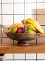 Light wooden countertop, bowl of fruits, stack of cups, tiled backsplash, oven