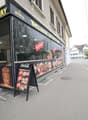 A restaurant with glass walls, a menu board, and outdoor seating.