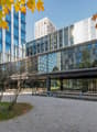 modern office building with glass facade, graveled outdoor seating area, glass covered entrance, greenery