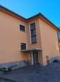 3-story house, beige exterior, double windows, carport, gravel driveway, car parked