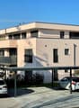 Three story house, white exterior, metal balcony, covered parking, two cars in carport, two cars in street