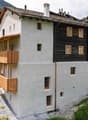 Modern design, white walls, black accents, terracotta roof, wooden balconies, large windows, situated on a hillside with a sloped terrain