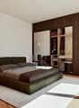 Spacious bedroom with a large bed, dark wood furniture, and built-in wardrobe. The room has hardwood floors and neutral-colored walls, creating a cozy and modern atmosphere.