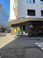 Modern building with glass windows, balcony, and a shopfront with a glass door and windows