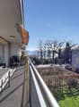 Balcony with glass railings, table, chairs, potted plant, awning, view of mountains and trees