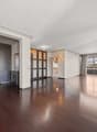 Spacious open-concept living area with hardwood floors, large windows, and a balcony. The room features a modern design with a built-in shelving unit dividing the space. The apartment appears to have a kitchen and other rooms beyond the living area.