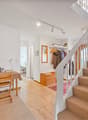 white walls, wooden floor, carpeted stairs, clothes hanging on wall, table and chair