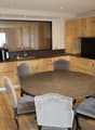 Modern kitchen with wooden cabinets, a round dining table, wooden floor, a sink with faucet, oven and refrigerator