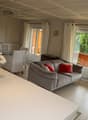 gray sofa, white chairs, glass table, flowers in a vase, sliding glass doors, balcony
