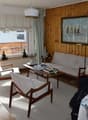 wooden walls, white rug, couch, chair, table with books, balcony, window with view