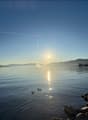 Wide view of a lake at sunset with ducks swimming in the foreground