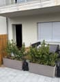 Wooden barriers with plants, tiled patio, patio furniture with plants, bicycle, white blinds, a window, an open doorway