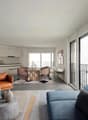 open floor plan, large windows, balcony, modern furnishings, neutral color scheme