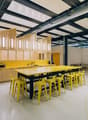 large open room with yellow counters and barstools, kitchen area with modern appliances, industrial style ceiling