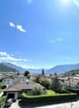 Town with mountains in the background, brick houses, tiled roofs, a car parked in front of one house, another car parked in a garage.