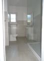 Bathroom with tile flooring, shower, sink, toilet, and a heater.