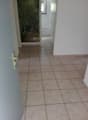 Empty hallway with tiled floor, white walls, open door, and a mural on the wall.