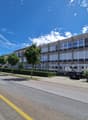 Multistory building, modern architecture, concrete exterior, numerous windows, parking area, streetlight, multiple parked cars