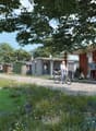 Modern homes with green exterior, garden with flowers, paved pathway, people with bicycles and chairs