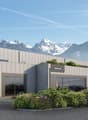 Modern two-story commercial building, grey exterior, glass windows, green roof, mountain view, multiple garage spaces, pedestrian area