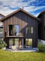 modern architecture, wooden panels, large windows, balcony, grassy yard, sitting area