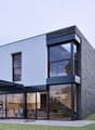 Modern design house, two floors, large windows, terrace with pergola, black metal chairs, green hedge